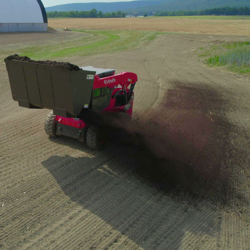 Compost Spreader spreading topsoil on grass seed.